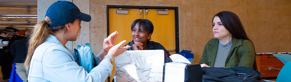 3名学生在皮马大学西校区的学生休息室讲美国手语